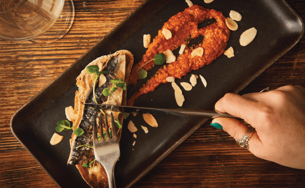 Woman cutting into mackerel dish